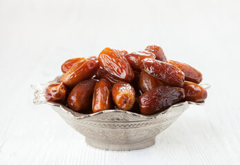 Bowl full of dates on a white wooden background. - 766208954