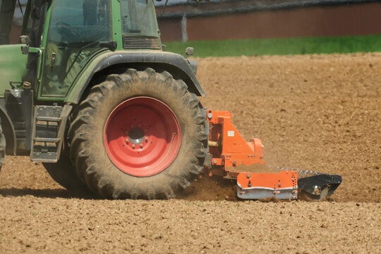 Traktor bestellt das Feld mit der Fr&auml;se im Fr&uuml;hjahr