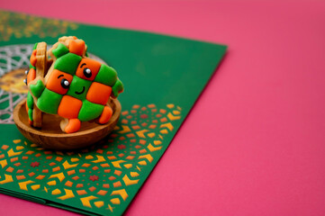 "Ketupat" butter cookies served on small wooden bowl, on green decorative paper; isolated on pink background. A close-up and selective focus photo of the cookie. A copy space. 