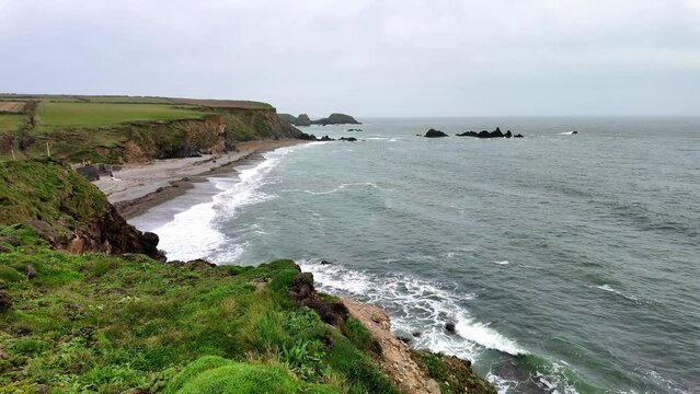 Clifftop view of surf breaking on secluded beach in spring on the Coast of Waterford Ireland