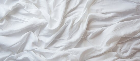 Minimalistic setting of a bed adorned in all white with a bed spread, pillow, and blanket