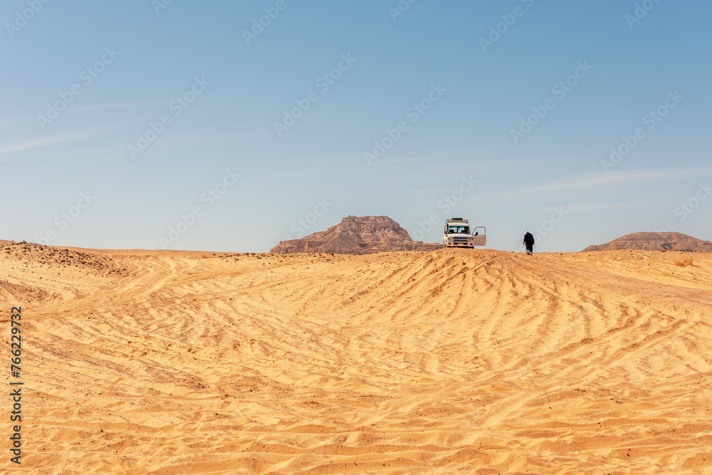 Wall mural bedouin walks next to the white car in the sinai desert. egypt.