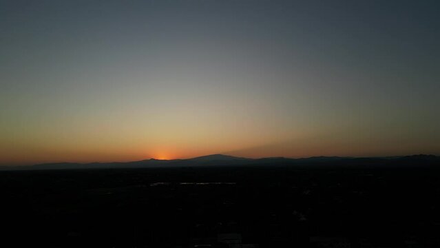 Take a photo of the backlit mountain view with an orange sun.