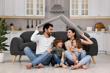 Family housing concept. Happy woman and her husband forming roof with their hands while sitting...
