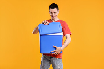 Man with blue cool box on orange background