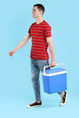 Man with cool box walking on light blue background