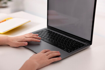 E-learning. Girl using laptop during online lesson at table indoors, closeup
