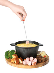 Woman dipping piece of ham into fondue pot with tasty melted cheese on white background, closeup