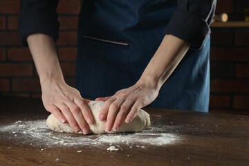 Obraz na płótnie Canvas Making bread. Woman kneading dough at wooden table in kitchen, closeup