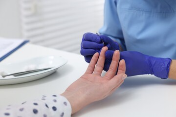 Laboratory testing. Doctor taking blood sample from patient at white table in hospital, closeup
