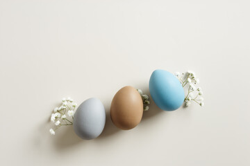 Easter Aesthetic with Matte Eggs and Delicate Florals, painted chicken egg decorated white flowers, top view on beige background, spring holiday concept. Minimal style pattern in pastel tones