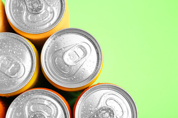 Energy drinks in wet cans on green background, top view. Space for text