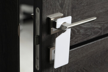 Wooden door with blank hanger on metal handle, closeup