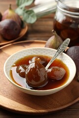 Bowl of tasty sweet fig jam on wooden table