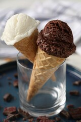 Tasty ice cream scoops in waffle cones and chocolate crumbs on table, closeup
