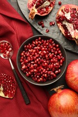 Tasty ripe pomegranates and grains on dark wooden table, flat lay