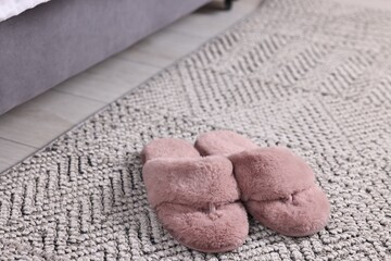 Pink soft slippers on carpet at home, closeup