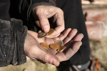 Poor homeless man holding coins outdoors, closeup