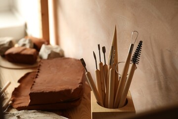 Clay and set of modeling tools on table in workshop, closeup