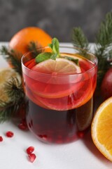 Christmas Sangria drink in glass, fir branches and fruits on white table, closeup