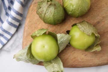 Fresh green tomatillos with husk on light table, top view