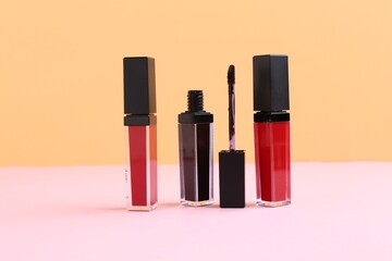 Different lip glosses and applicator on color background