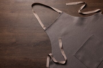 Stylish brown apron on wooden table, top view. Mockup for design