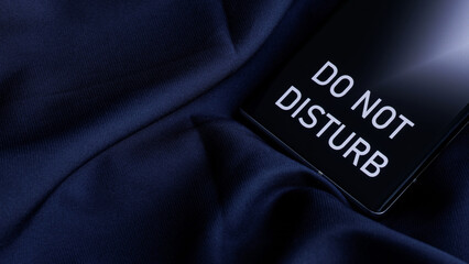 Smartphone cell phone with do not disturb inscription on dark blue silk fabric background. Concept...