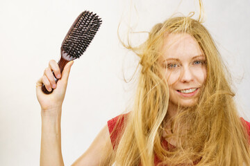 Blonde girl long blowing hair holds natural bristles brush - obrazy, fototapety, plakaty