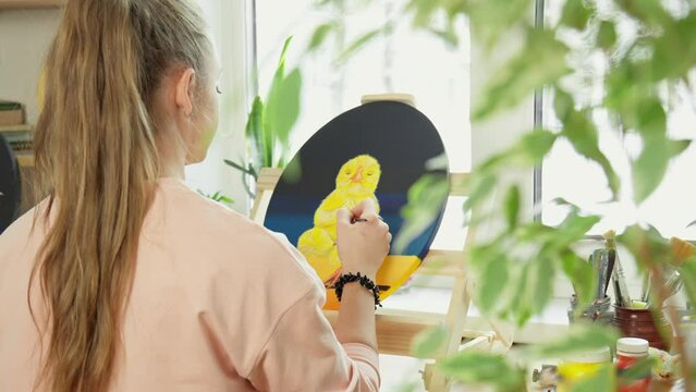 Talented female artist draws yellow chicken on canvas. Young woman painter drawing picture on canvas using acrylic Contemporary painter creating picture. Art therapy. paints. 4K, UHD