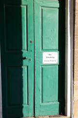 A "No Smoking, Private Property" sign on an old green door