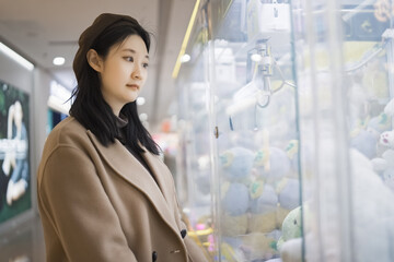 Young Woman Contemplating Choices at Claw Machine