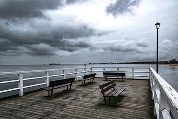 Pier on the sea coast and stormy sky