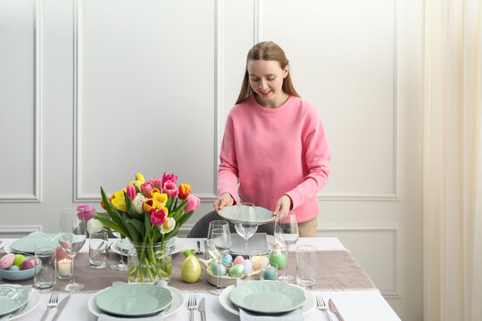 Woman setting table for festive Easter dinner at home