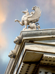 Obraz premium A Griffon statuette stands on the roof of Athens National University. Griffins were known for guarding treasures and priceless possessions. Cultural travel in Greece.