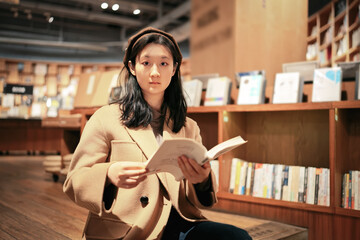 Young Woman Engrossed in Reading at Cozy Bookstore