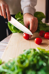 A close up of girl's or woman's hands peeling and cutting vegetables with knife making salad	