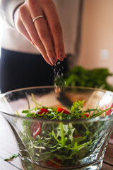 A close up of girl's or woman's hands peeling and cutting vegetables with knife making salad	