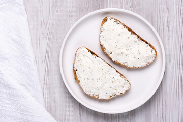 Sandwiches with soft curd cheese on a white wooden table