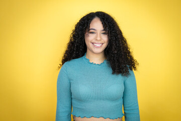 African american woman wearing casual sweater over yellow background with a happy face standing and...