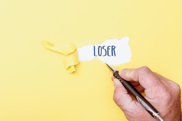 Loser, word written on ripped paper background