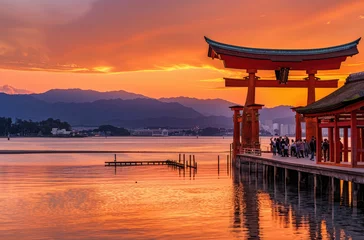 Tuinposter The red torii gate of Itsuk Japanese temple stands on the water surface at sunset © Kien
