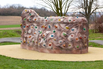 Small artificial climbing wall with colourful grips in park