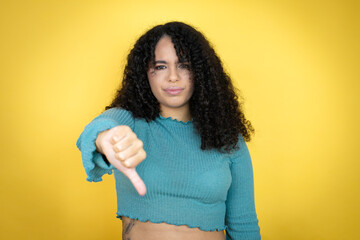 African american woman wearing casual sweater over yellow background with angry face, negative sign...