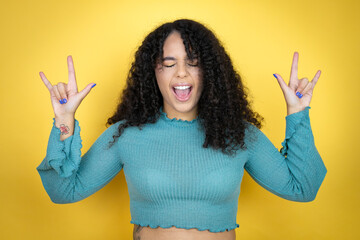 African american woman wearing casual sweater over yellow background shouting with crazy expression...