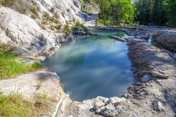 Fototapeta na wymiar Bagni San Filippo, Natural pool with turquoise water, white rocks, and lush vegetation in Tuscany, Italy