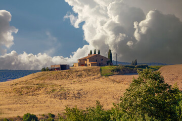 Scenic Tuscan farmhouse in Val d'Orcia with cypress trees, rolling hills, and distant view of Pienza - 766301599