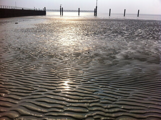 The suns light is mirrored on the waters surface at the beach Emden Germany