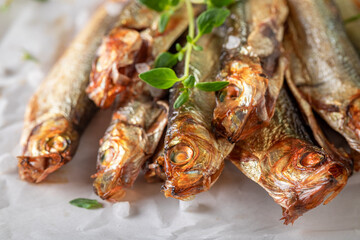 Tasty and salty smoked sprats as appetizer by the sea. - obrazy, fototapety, plakaty