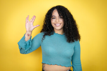 African american woman wearing casual sweater over yellow background doing star trek freak symbol